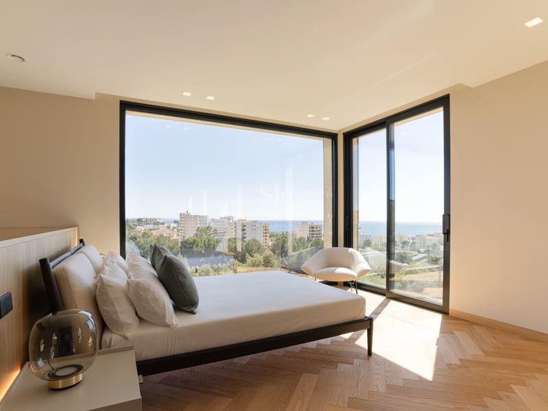 Chambre principale lumineuse avec fenêtres d'angle du sol au plafond, vue sur la mer et parquet en chevrons.