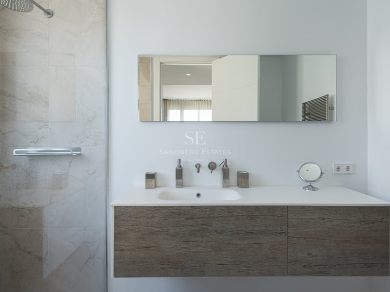 Salle de bains moderne avec meuble vasque suspendu en bois, paroi de douche en verre et finitions chromées.
