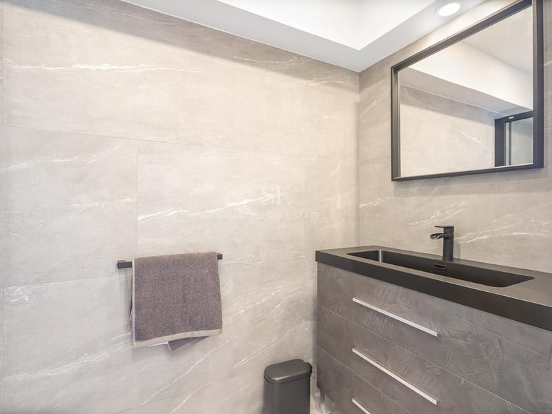 Vanité de salle de bain avec carreaux de pierre grise, vasque intégrée noire et miroir à cadre noir.