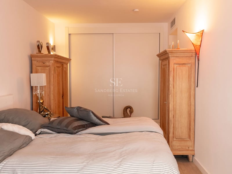 Chambre lumineuse avec grand lit, deux armoires en bois et placards intégrés sous un éclairage d'ambiance chaleureux.