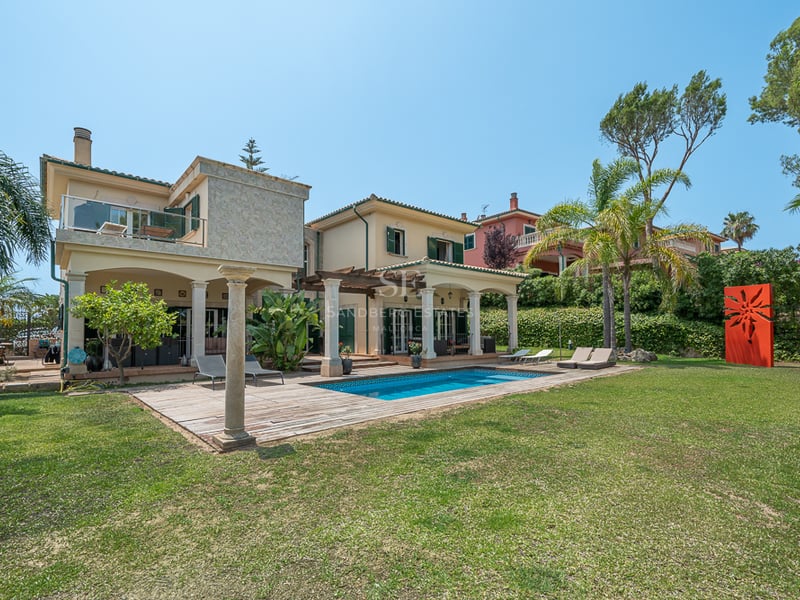 Extérieur de villa de luxe avec piscine, terrasse en bois, grand jardin et architecture méditerranéenne traditionnelle.