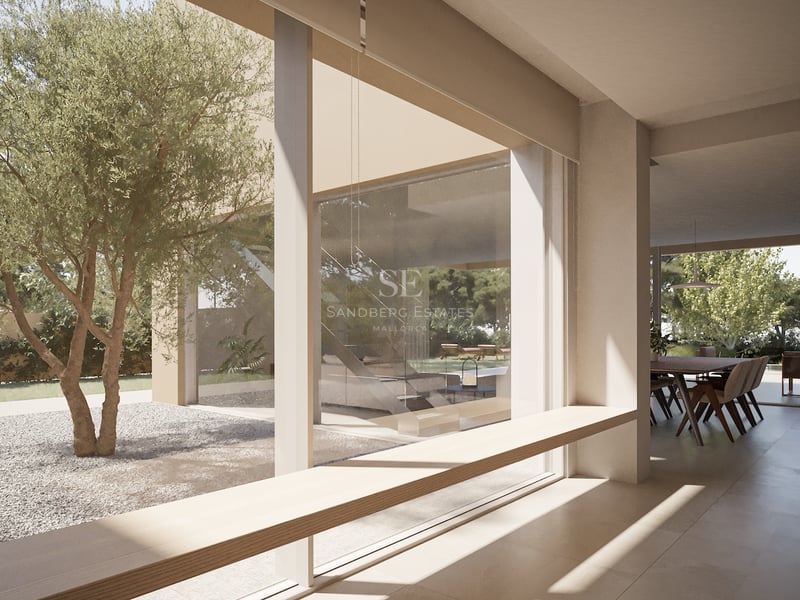 Intérieur minimaliste avec une banquette en bois devant de larges baies vitrées donnant sur un olivier.