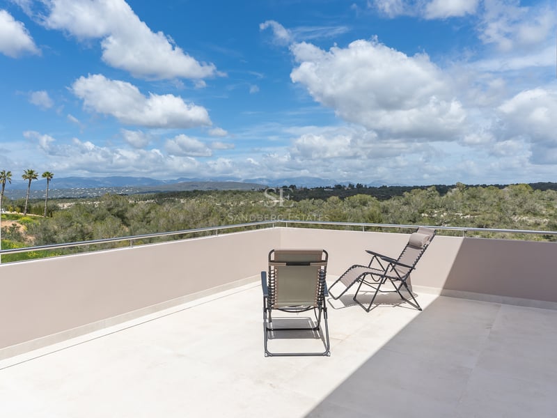 Toit-terrasse avec deux chaises longues offrant une vue sur une vallée verdoyante et des montagnes lointaines.