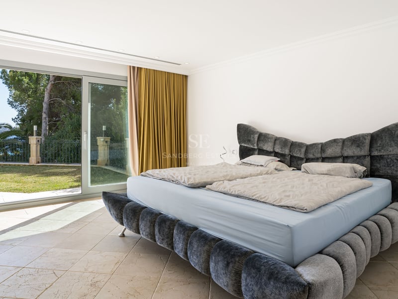 Chambre parentale contemporaine avec lit en velours gris et grandes baies vitrées ouvrant sur le jardin.