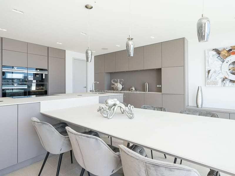 Cuisine contemporaine avec placards taupe, un grand îlot blanc et des chaises de salle à manger en velours gris.