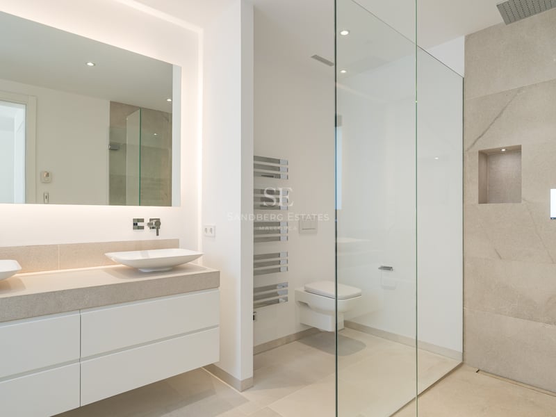 Salle de bain moderne avec double vasque, miroir rétroéclairé et douche à l'italienne avec carreaux en pierre.