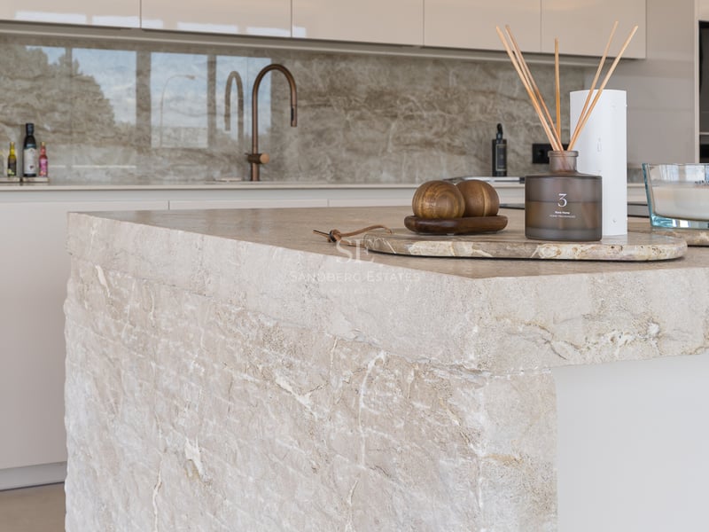 Gros plan d'un îlot de cuisine en pierre naturelle avec robinetterie en cuivre et décoration minimaliste.