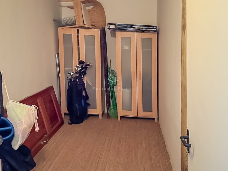 Vue intérieure d'un débarras avec des armoires en bois, des sacs de golf et un tapis en sisal.