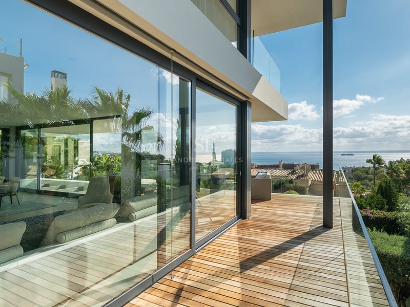Terrasse moderne en bois avec garde-corps en verre offrant une vue panoramique sur la mer Méditerranée.