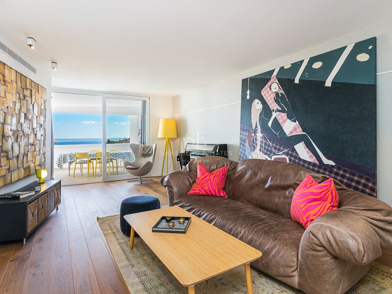 Intérieur lumineux avec balcon et vue sur la mer. Design moderne avec parquet et mobilier élégant. De grandes fenêtres maximisent la lumière naturelle.