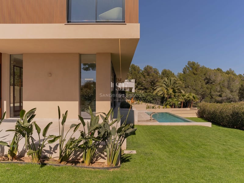 Profil latéral d'une villa moderne à deux étages avec murs couleur sable, accents en bois, pelouse et piscine.
