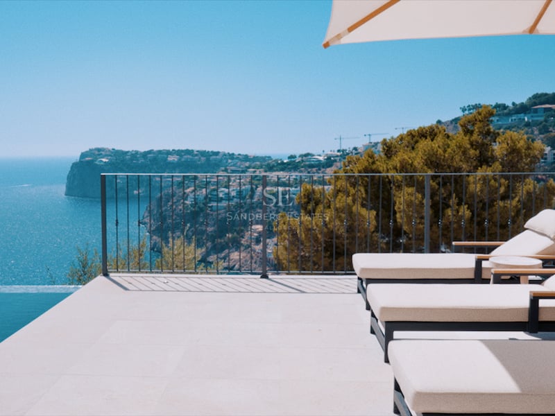 Terrasse de luxe avec chaises longues blanches et parasol à côté d'une piscine à débordement surplombant la mer.