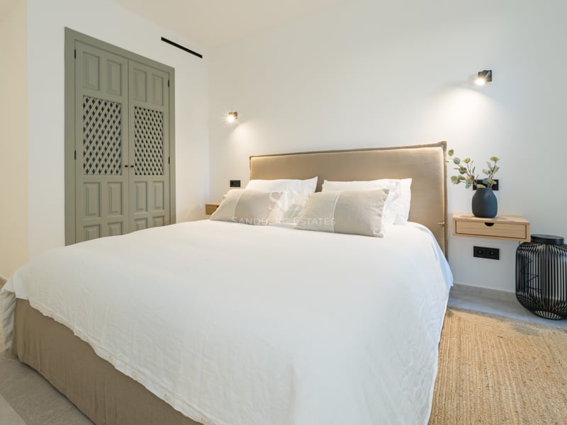 Chambre avec lit double, tête de lit en lin, tables de chevet flottantes en bois et portes de placard vert sauge.