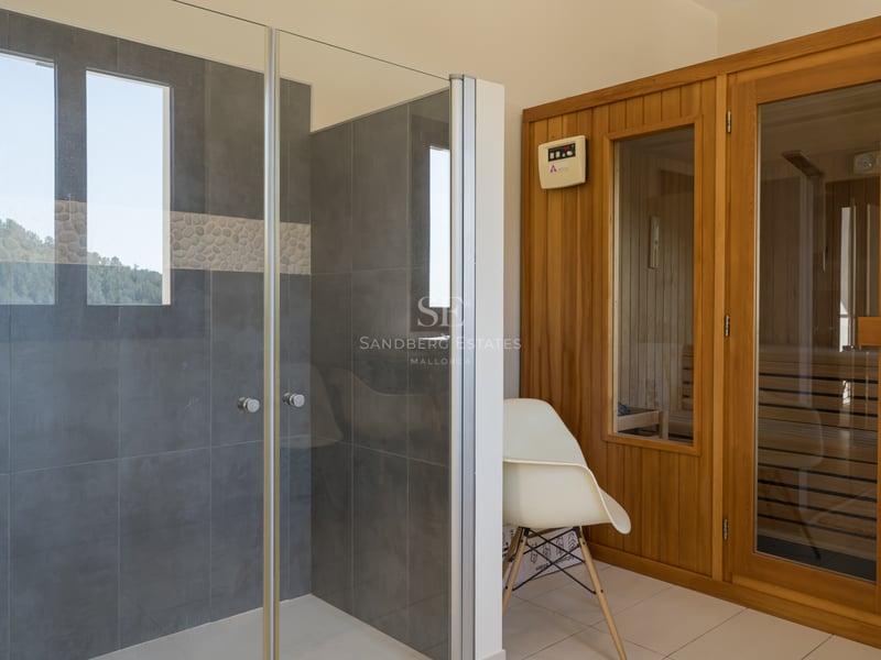 Espace spa avec douche vitrée, carrelage gris et sauna en bois naturel au design contemporain.