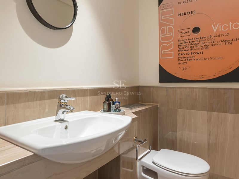 Salle de bains moderne avec lavabo en porcelaine, carrelage en marbre beige et décoration murale pop art.