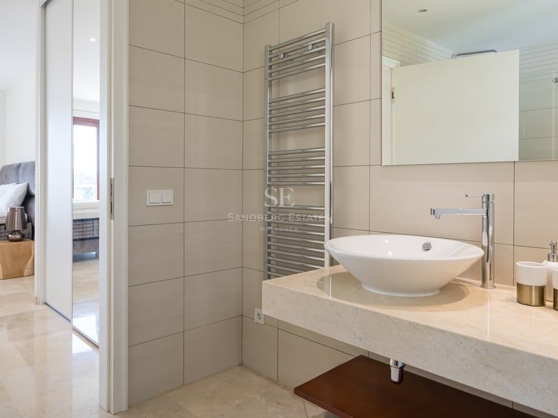 Salle de bains moderne avec doubles vasques, plan de travail en marbre crème et sèche-serviettes chauffant.
