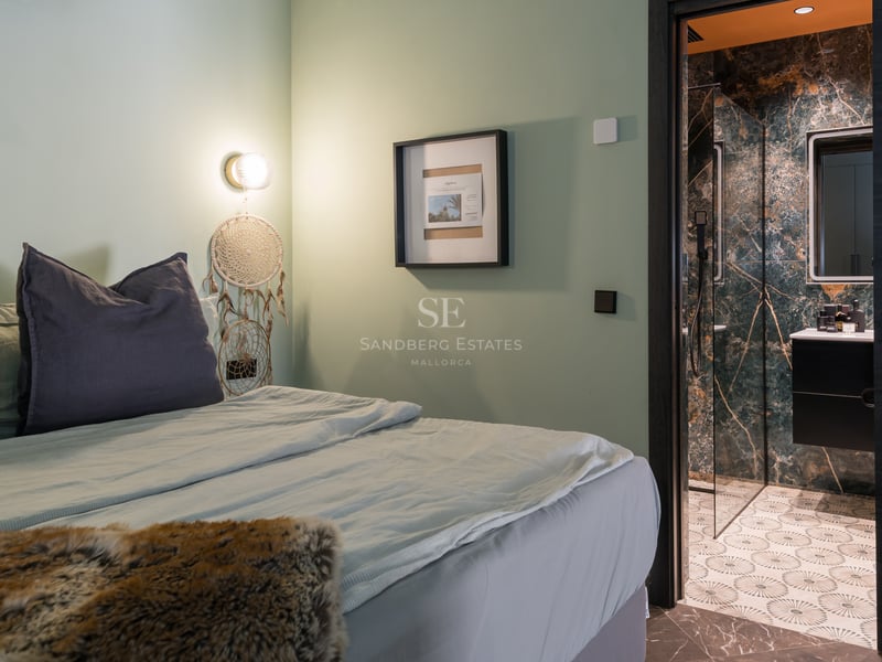 Chambre moderne aux murs vert sauge avec vue sur une salle de bain en marbre vert foncé.