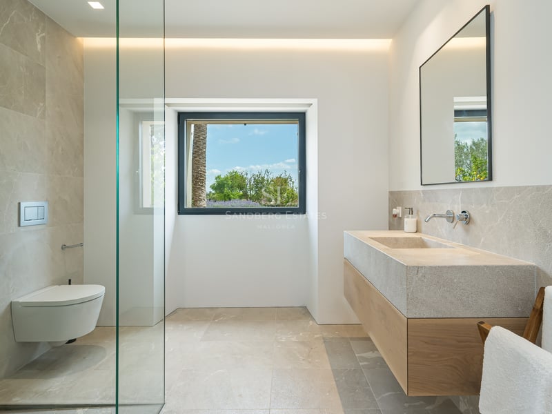Salle de bain contemporaine avec vasque suspendue en pierre, douche à l'italienne vitrée et vue sur le jardin.