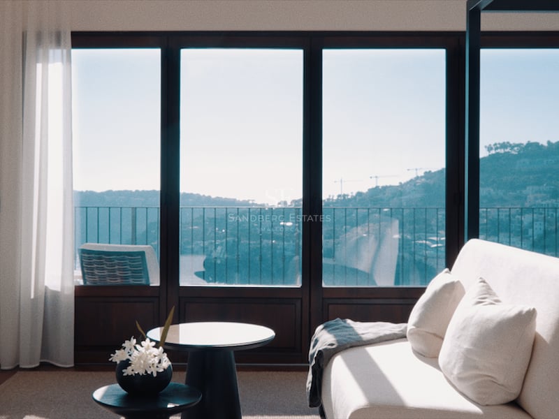 Chambre principale moderne avec canapé blanc, lit à baldaquin et baies vitrées offrant une vue sur la mer.