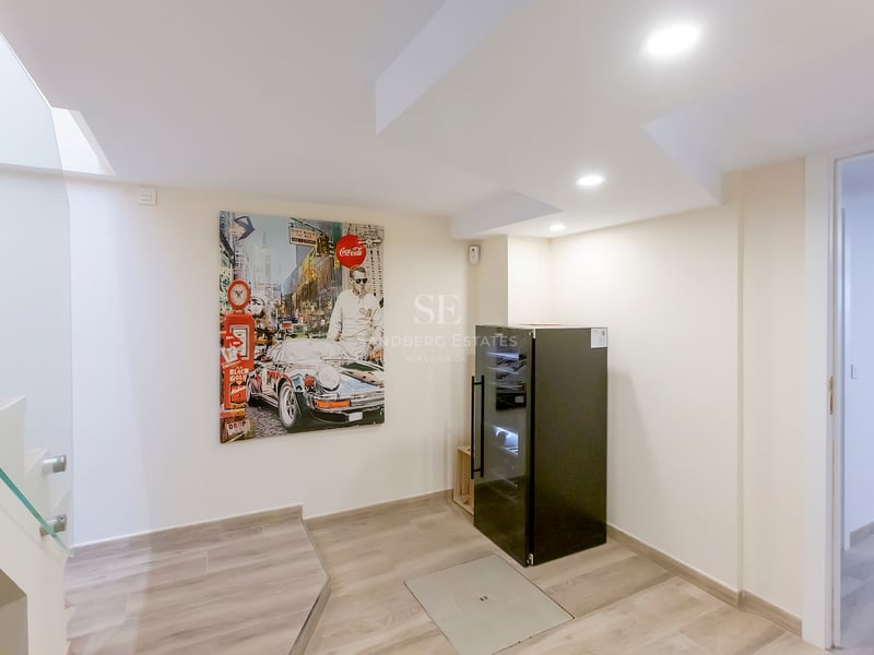Intérieur moderne avec une peinture pop-art de voiture, une cave à vin noire et un escalier en verre.