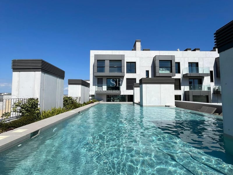 Longue piscine de toit aux eaux turquoise avec bordures en pierre devant un immeuble d'appartements moderne blanc et gris.