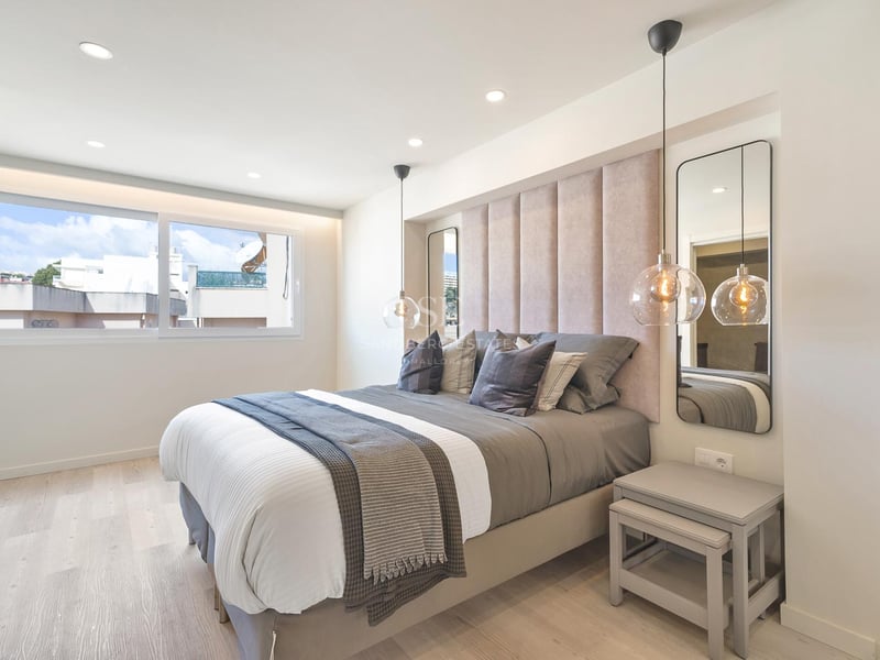 Chambre contemporaine avec tête de lit capitonnée, suspensions en verre et parquet en bois clair.