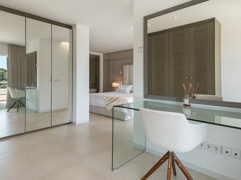 Chambre de maître moderne avec placards miroir, coiffeuse en verre et accès terrasse.