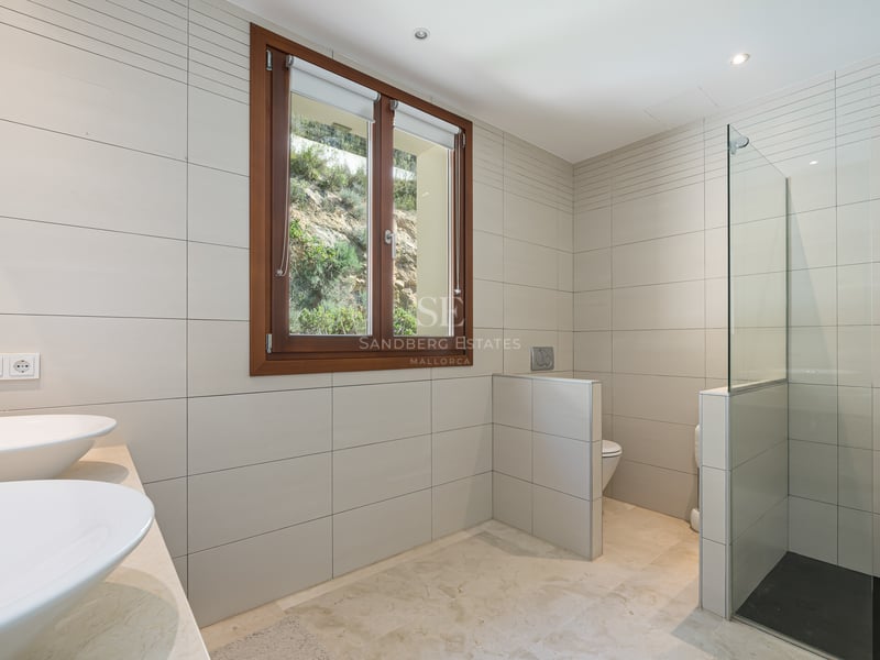 Salle de bain moderne avec doubles vasques, douche vitrée au sol en ardoise et fenêtre en bois.