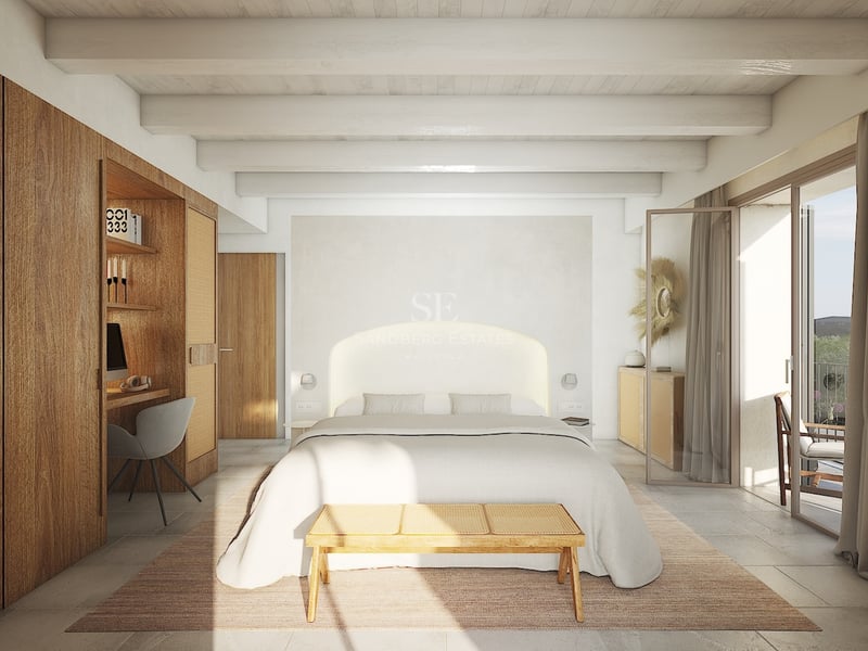 Dormitorio luminoso con vigas blancas, armarios de madera con escritorio, cama amplia y acceso al balcón.