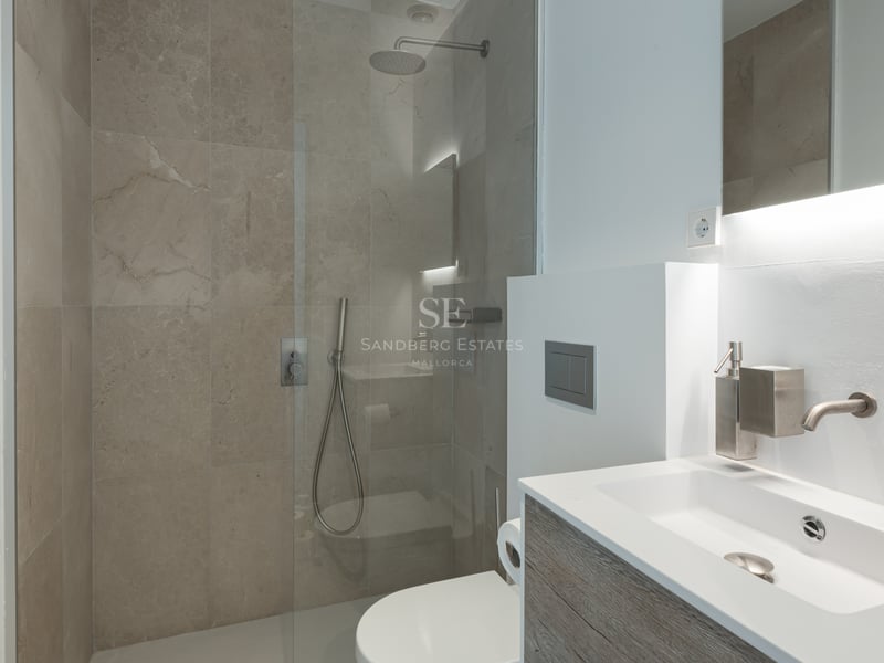 Salle de bains contemporaine avec carrelage en pierre, douche vitrée, meuble vasque suspendu et sèche-serviettes.