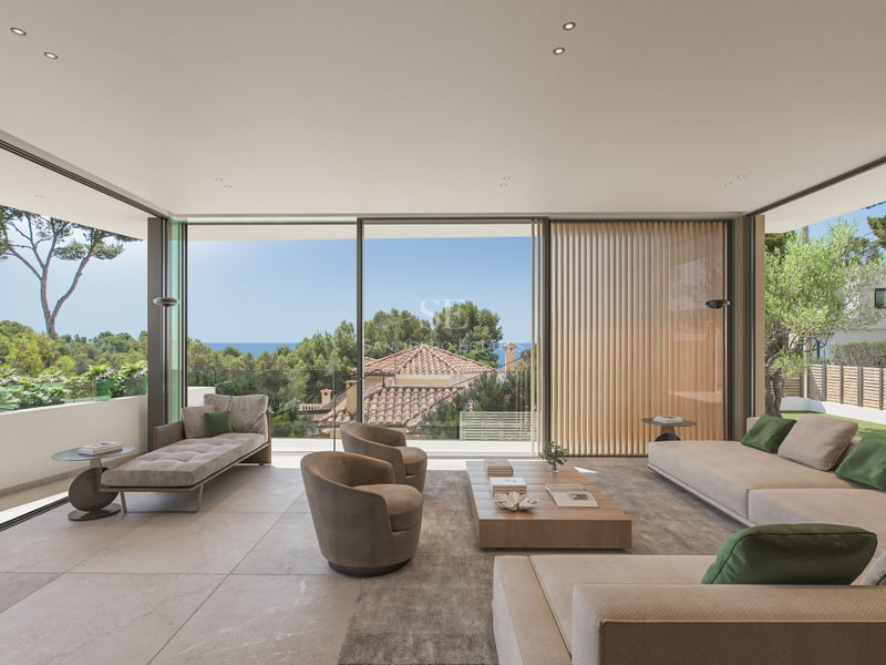 Salon moderne avec baies vitrées, canapés beiges, table en bois et vue sur la mer et les arbres.