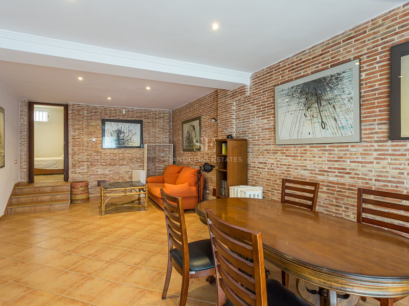 Salle à manger avec table en bois et canapé orange devant un mur en briques apparentes dans un intérieur chaleureux.