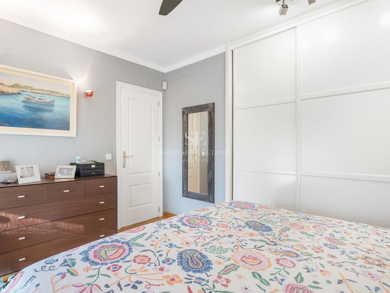 Chambre d'amis lumineuse avec grands placards coulissants blancs, commode en bois foncé et literie fleurie.