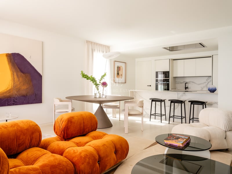 Salon contemporain avec canapé modulaire orange, table à manger ronde et îlot de cuisine en marbre en espace ouvert.