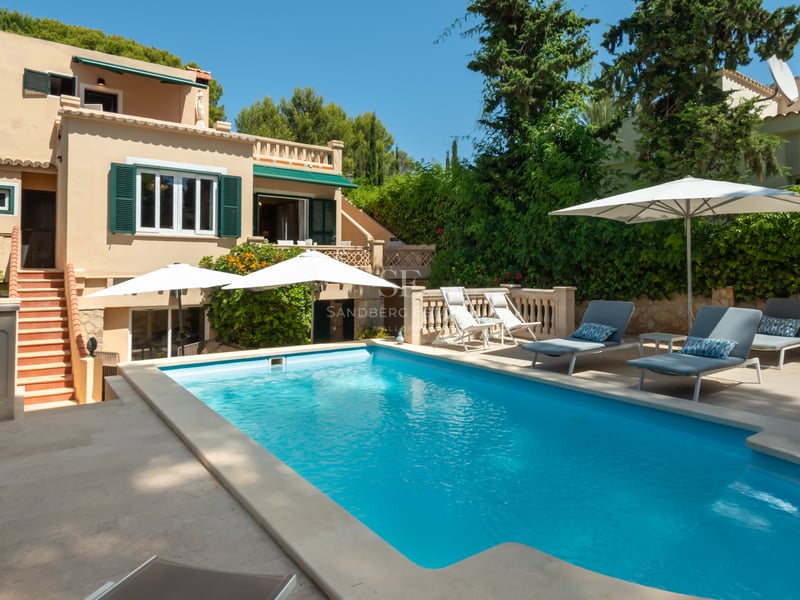 Piscine privée aux eaux turquoises entourée d'une terrasse en pierre et d'une villa méditerranéenne ocre.