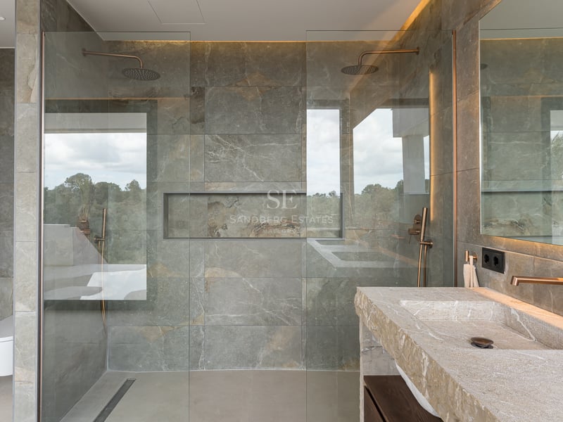 Salle de bain contemporaine avec carrelage en pierre grise, paroi en verre et vasque en pierre naturelle.