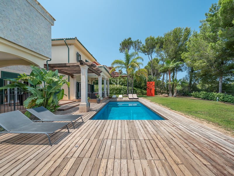 Piscine extérieure rectangulaire entourée d'un deck en bois, transats et jardin méditerranéen luxuriant.