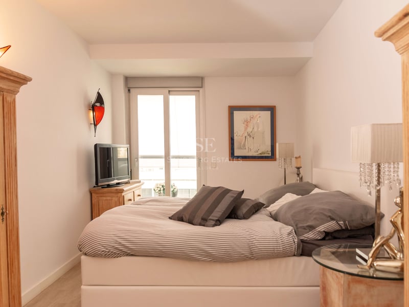Chambre à coucher avec un grand lit, des meubles en bois, des lampes en cristal et un balcon attenant.