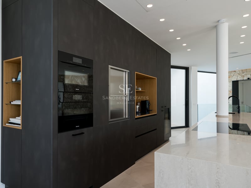 Cuisine moderne avec placards anthracite, îlot en marbre et fours Miele intégrés dans un espace lumineux.