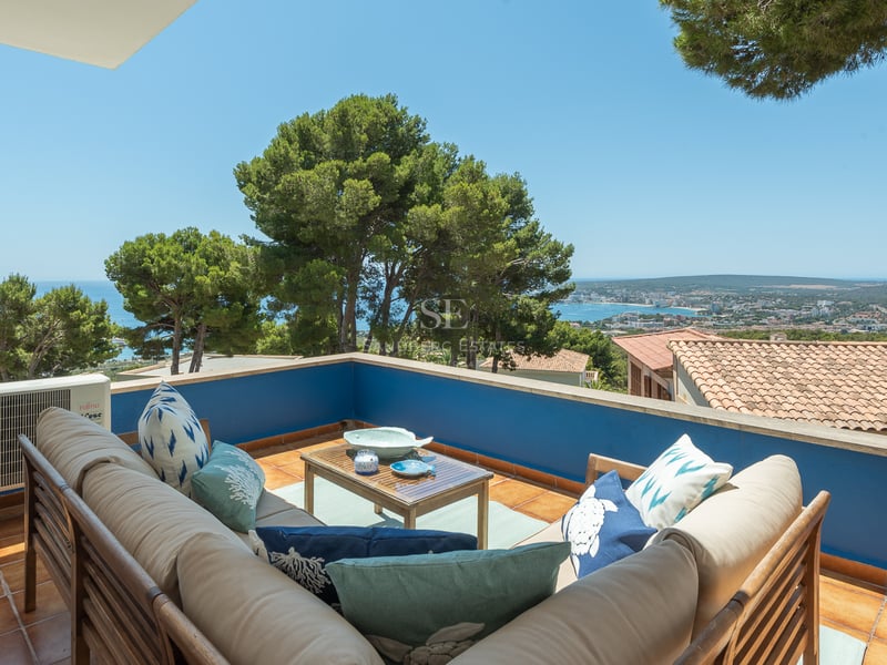 Terrasse extérieure avec canapé en L, murs bleus et vue panoramique sur la côte méditerranéenne.