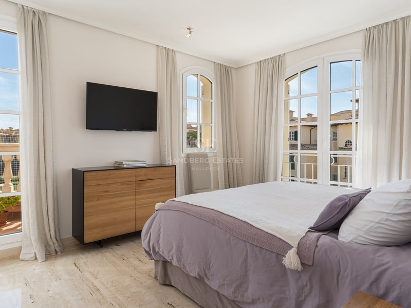 Chambre élégante avec lit parme, sol en travertin, grandes fenêtres cintrées et accès au balcon.