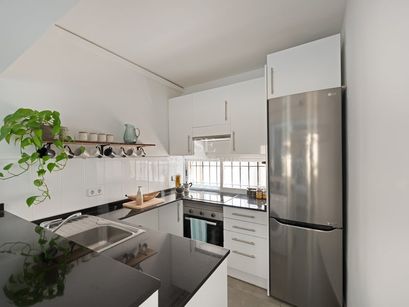 Cuisine contemporaine avec placards blancs, plans de travail en granit noir et appareils en acier inoxydable.