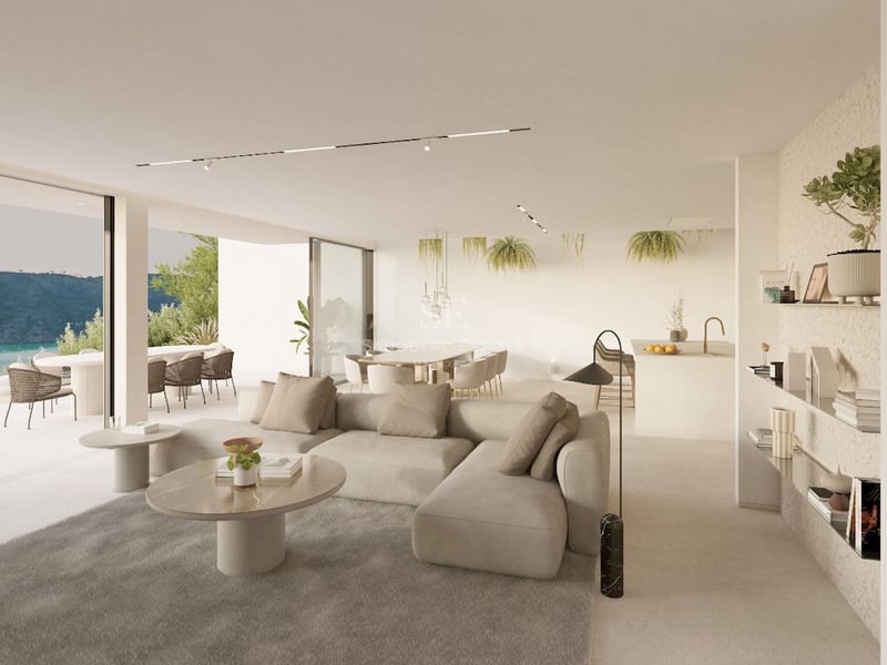 Salon minimaliste ensoleillé avec canapé beige, tables en marbre et grandes baies vitrées ouvrant sur une terrasse.