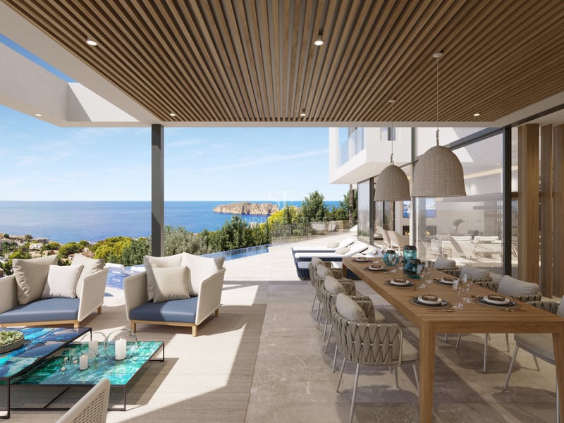 Terrasse couverte avec grande table à manger en bois, salon de jardin et piscine à débordement face à la mer.