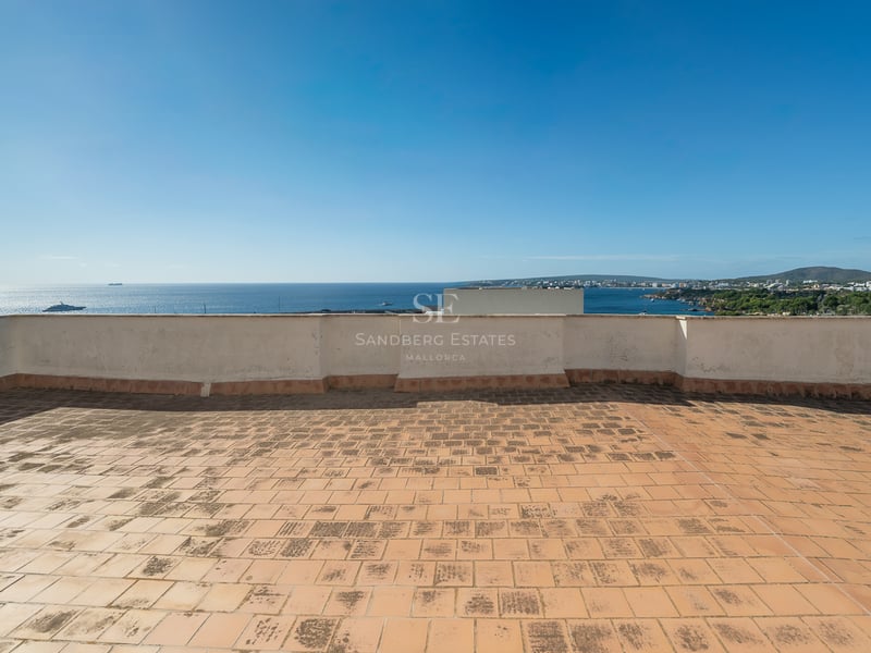 Toit-terrasse en terre cuite avec vue imprenable sur la mer Méditerranée et le littoral sous un ciel bleu.