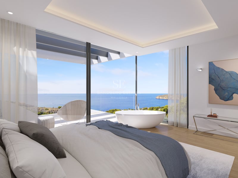 Chambre de luxe avec baignoire îlot et baies vitrées d'angle donnant sur la mer Méditerranée.