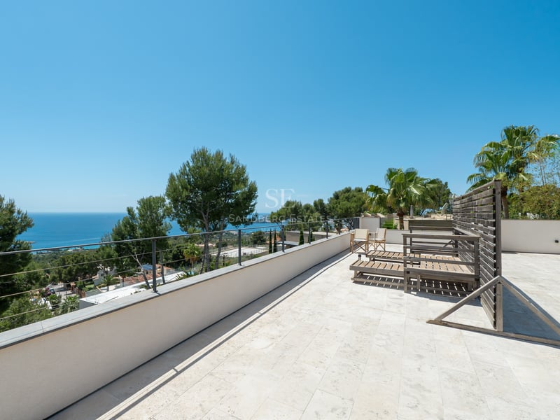 Grande terrasse en pierre avec chaises longues offrant une vue sur la mer Méditerranée et la nature.