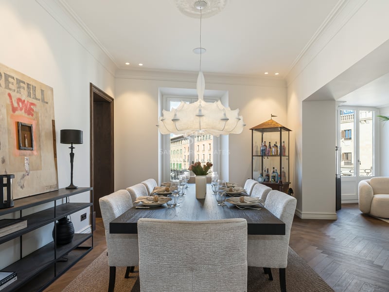 Contemporary dining room with dark wood table, upholstered chairs, designer chandelier, and oak herringbone floors.