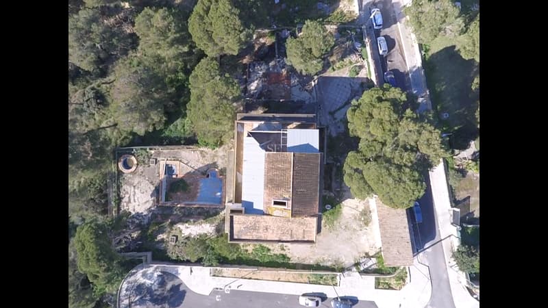 Luftaufnahme von oben auf ein Haus mit Ziegeldach, leerem Pool und umliegenden Pinien.