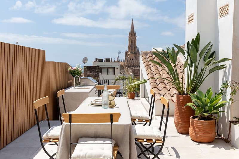 Moderne Dachterrasse mit Essbereich im Freien, Außenküche und Blick auf eine historische gotische Kathedrale.